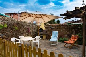 a patio with a table and chairs and an umbrella at Monolocale con veranda e giardino a Rio Marina in Rio Marina