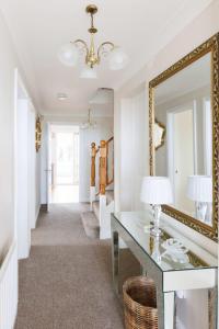 a hallway with a mirror and a desk with a lamp at Spacious 4-Bed Seaside Retreat in Selsey in Selsey