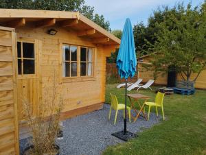 a small wooden cabin with a table and an umbrella at Verton, Gîte Les chalets du Fliers Meublés de tourisme classés 2 étoiles plage de BERCK SUR MER in Verton +36 photos