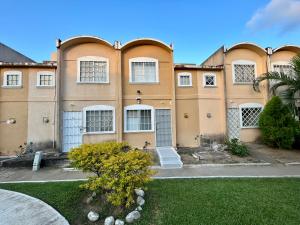 a large tan building with white windows and a yard at Hermosa Casa Con Alberca AC in Ixtapa