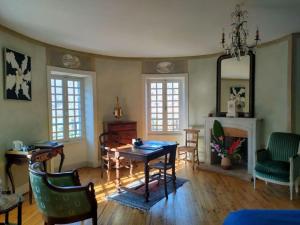 a living room with a table and chairs and a fireplace at Chateau Ol Puech in Vic-sur-Cère