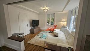 a living room with a white couch and a television at Le Pavillon dans le Parc in Saulxures-sur-Moselotte