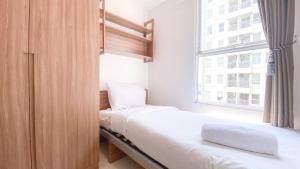 two beds in a small room with a window at Nice and Homey 2BR at Citra Living Apartment By Travelio in Jakarta +11 photos