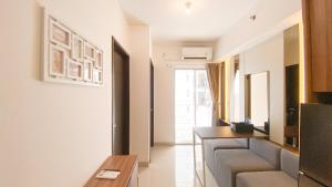a living room with a couch and a table at Nice and Homey 2BR at Citra Living Apartment By Travelio in Jakarta