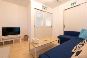 a living room with a blue couch and a tv at アンドステイ西戸部町2丁目 in Nishi-hiranumachō