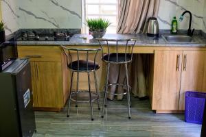 a kitchen with two bar stools and a sink at Builders Homes and Apartments in Ibadan