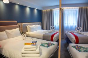 a hotel room with two beds and a mirror at Holiday Inn Express Royal Docks by IHG in London