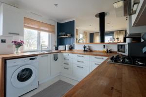 Una cocina con gabinetes blancos y lavadora y secadora. en Secluded Sanctuary On The River, en Christchurch