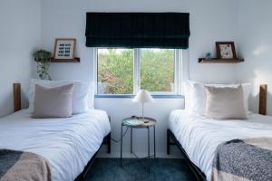 Dos camas en una habitación con ventana. en Secluded Sanctuary On The River, en Christchurch