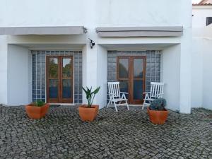 a white house with two chairs and potted plants at Alto da Praia Villa in Colares