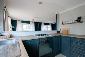 a kitchen with blue cabinets and a stove top oven at Peaceful Riverside Family Retreat in Christchurch +10 photos