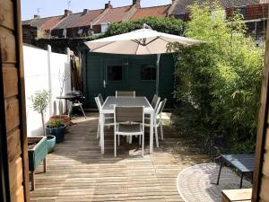 a patio with an umbrella and a table and chairs at Jolie maison de ville au calme in Marcq-en-Baroeul