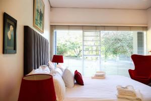 a bedroom with a bed with a red chair and a window at Vaal River Garden Cottage in Theoville