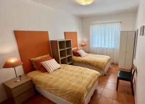 a bedroom with two beds and a table and a lamp at Carvoeiro terrace - Stay in the heart of Carvoeiro in Carvoeiro