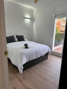 a black cat sitting on a bed in a bedroom at Ático gran terraza cerca BCN in Castelldefels