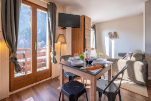 a living room with a table and a couch at Le Petit Aravis - village et vue panoramique in La Giettaz