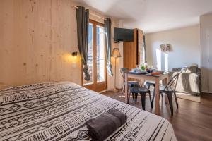a hotel room with two beds and a table and a dining room at Le Petit Aravis - village et vue panoramique in La Giettaz +5 photos