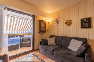 a living room with a couch and a sliding glass door at La Favière proche de la plage in Bormes-les-Mimosas