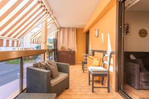 a living room with a balcony with a couch and chairs at La Favière proche de la plage in Bormes-les-Mimosas
