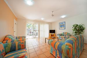 a living room with two couches and a table at at Beach Court Holiday Villas in Airlie Beach