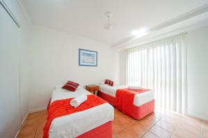 a bed room with two beds and a table at at Beach Court Holiday Villas in Airlie Beach