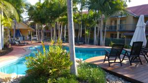 a resort with a swimming pool with chairs and an umbrella at at Beach Court Holiday Villas in Airlie Beach