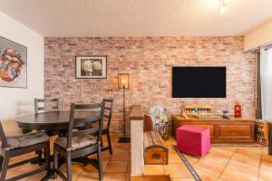 a living room with a brick wall and a tv at La Favière proche de la plage in Bormes-les-Mimosas