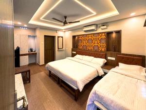 a hotel room with two beds and a television at Srishty Garden Resorts in Tenkāsi