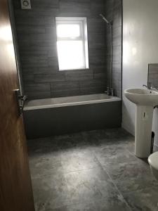 a bathroom with a bath tub and a sink at 4 Bedroom Contractors House in Sheffield