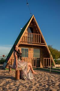 a woman sitting on a bench in front of a house at Chale Flores Do Velho Chico in Casa Nova