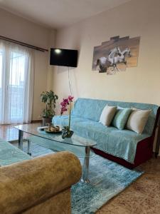 a living room with a blue couch and a glass table at Alexandra's Studio pyli in Pýli