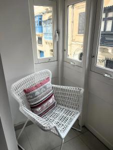 a white chair with a pillow on it in a room at Maltese Coastal Escape in Sliema