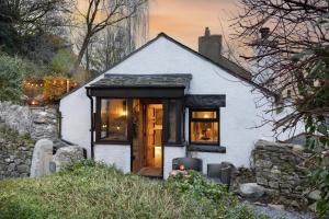 una piccola casa bianca con una porta in legno di Mead Cottage a Tranquil Retreat in the Heart of the Lake District a Lindale