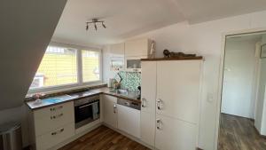 a small kitchen with white cabinets and a window at Feine 2-Zimmer Dachgeschoßwohnung in Klagenfurt