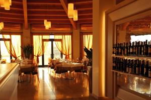 un restaurante con mesas, sillas y botellas de vino en Grand Hotel Forlì en Forlì