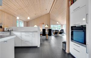 a kitchen with white cabinets and a dining room at Amazing Home In Ålbæk With Sauna in Ålbæk +22 photos