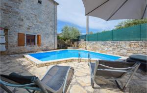a swimming pool with two chairs and an umbrella at Lovely Home In Visnjan With Wifi in Višnjan