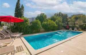 a swimming pool with a red umbrella and chairs at 2 Bedroom Lovely Apartment In Salatici in Salatić +22 photos