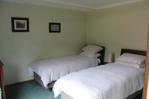two beds in a room with white sheets at Eagle's Roost Farmstay B&B in Rocky Cape