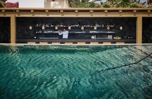 a man standing in front of a bar next to a swimming pool at Istoria, a Member of Design Hotels in Perivolos