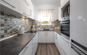 une cuisine avec des armoires blanches et une fenêtre dans l'établissement 3 Bedroom Nice Home In Kapovci, à Brusići
