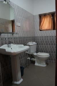 a bathroom with a sink and a toilet and a mirror at Tandem Guesthouse in Hikkaduwa