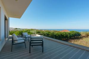 a deck with chairs and a table and a view of the ocean at Villa Beach and Friends with ocean view in Lourinhã