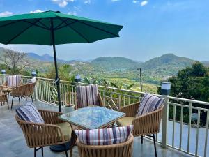 Un patio con sillas y una mesa con sombrilla. en Alaya Stays 2 BHK Villa With Scenic views - Peace, en Bhimtal 93 fotos más
