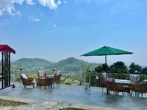 Un patio con sillas, una mesa y una sombrilla. en Alaya Stays 2 BHK Villa With Scenic views - Peace, en Bhimtal