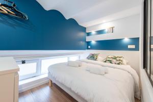sypialnia z białym łóżkiem i niebieską ścianą w obiekcie LE CHANCEUX fabuleux duplex en design, pour loisir en couple ou congrès w Cannes