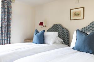 a bedroom with two beds with blue pillows at The Black Bull Hotel in Duns