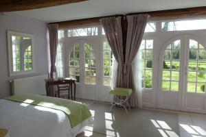 a bedroom with a bed and large windows at Chambres d'hôtes du Bas Manoir in Bretteville-sur-Odon