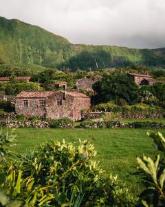 an old house in a field with mountains in the background at Aldeia da Cuada in Faja Grande