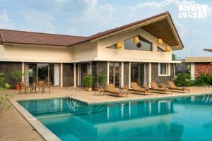a villa with a swimming pool and a house at StayVista at Solaris with Pool, Lawn & BBQ in Alibaug